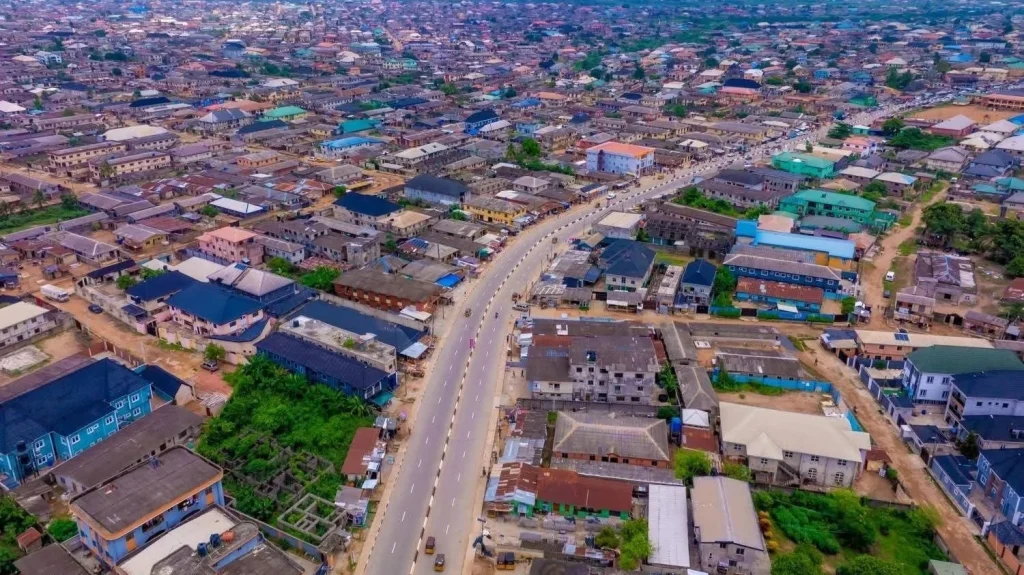 Aerial view of a densely populated Nigerian city with residential buildings, commercial properties and a major paved road.